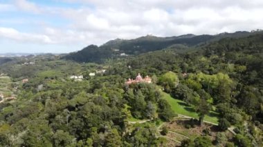 Monserrate Sarayı 'nın pembe kubbesi Sintra' nın tepelerinde, ormanlarla çevrili. Pena Sarayı uzak bir tepenin arkasında görünür..