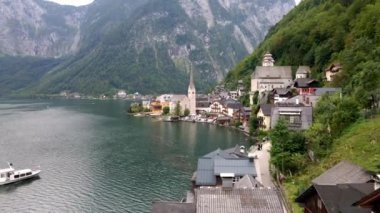 Avusturya 'daki Hallstatt' te Evanjelik Kilise kulesi, geleneksel mimari, ormanlı dağlar ve Hallstatter 'de bir tekne bulunur..