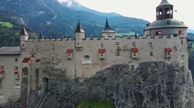 Hohenwerfen Şatosu, Avusturya 'daki orman dağlarına karşı kurulmuş ortaçağ kuleleri ve kırmızı ve beyaz bayraklı duvarlarıyla kayalık bir çıkıntının üzerinde duruyor..
