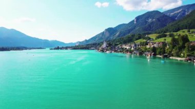 Avusturya 'da Wolfgang Gölü' nün yanında yer alan St. Wolfgang köyünde beyaz bir kilise kulesi, geleneksel mimari ve arka planda görkemli Alpler yer almaktadır..