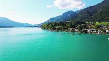 Avusturya 'daki Wolfgang Gölü' nde orman ve köylerle çevrili canlı turkuaz suları bulunur. Dağın arka planında kayıklar ve kürekçiler görülebilir..