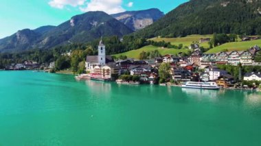 Pfarrkirche St. Wolfgang ile St. Wolfgang manzarası, turkuaz Wolfgangsee Gölü, geleneksel binalar ve arka planda Salzkammergut dağları..