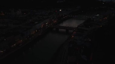 Geceleri Avusturya 'nın Salzburg kentinde Salzach Nehri, aydınlık binalar ve önemli bir köprü bulunur. Hohensalzburg Kalesi silueti tarihsel derinlik ekler..