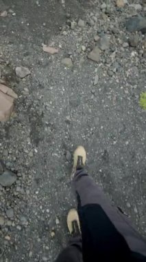 Karanlık volkanik kayalar ve İzlanda 'daki çakıl taşları üzerindeki yürüyüş botlarının havadan görünüşü zeminin engebeli arazisini ve dokusunu vurguluyor..