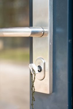 Metalik kapı kilidini kapat ve yeşil kabloya bağlı bir anahtarla tut. Koyu renk kapılı çerçeve fırçalı metal kaplamayla çelişiyor..