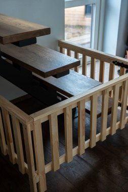 Modern ahşap merdiven, yüzen merdivenler ve pencerenin yanında açık renkli korkuluklar. Koyu zemin, dış mekan ahşap yapısı ile tasarımla çelişiyor..