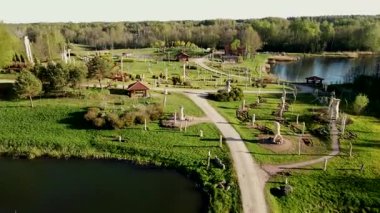 Kırsal bir parkta sanatsal ahşap heykeller, küçük bir gölet ve bir çardak bulunur. Dolambaçlı yollar ve çiçek tarlaları sık bir orman zeminine kurulur..