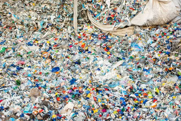 Renkli şişe kapakları ve parçalanmış molozlar da dahil olmak üzere yoğun bir şekilde paketlenmiş plastik atık, çevre kirliliği ve bozulma sorununu vurguluyor.