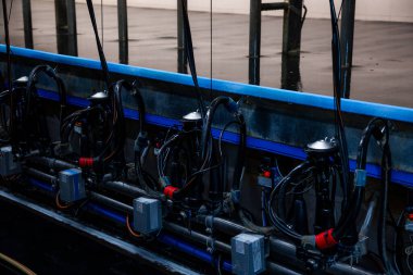 Metalik bir yapıda boruları, hortumları ve kontrol kutuları olan sağma makineleri. Islak zemin yakın zamanda temizlenmiş ya da tesiste kullanılmış..