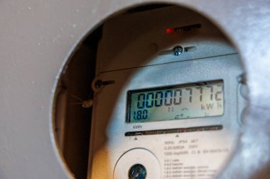 Dijital ekranlı elektrik sayacı 00000772 kW, kırmızı gösterge ışığı ve metal ya da plastik bir muhafaza üzerindeki teknik detayları gösteriyor.