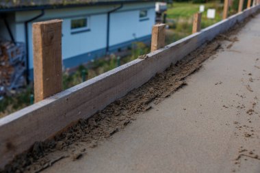 Beton ya da kumdan yapılmış ahşap bir çerçeve, dikey kazıklar ve mavi aksanlı beyaz bir bina..