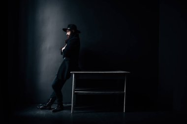 Sakallı bir adam pencereden dışarı bakar.