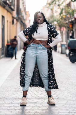 Kendine güvenen genç Afrikalı kadın kameraya bakıyor ve poz veriyor. Güzel örgüleri var..