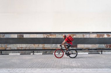 Afrikalı kurye bir paket taşıyor ve kaskla şehri bisikletle geçiyor..