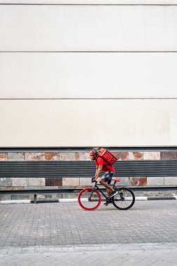 Afrikalı kurye bir paket taşıyor ve kaskla şehri bisikletle geçiyor..