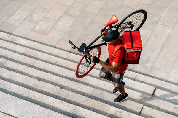 유명하지 배달부가 얼굴에 마스크를 자전거를 도시에서 물건을 배달하는 있습니다 — 스톡 사진