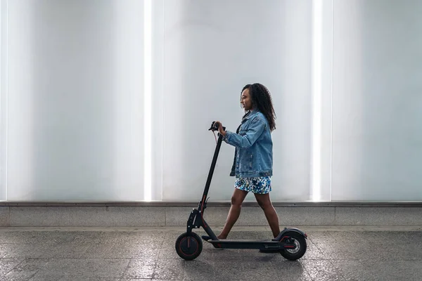 Csinos Afrikai Göndör Hajjal Sétál Elektromos Robogójával Elöl Néz — Stock Fotó