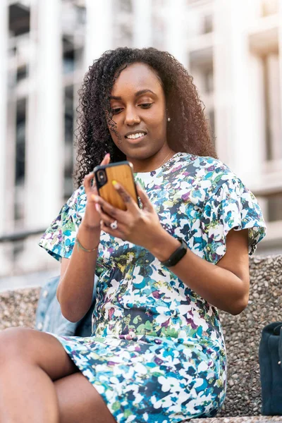 Прелестная Африканская Девушка Красочным Платьем Сидящая Мобильном Телефоне Развлекающаяся Городе — стоковое фото