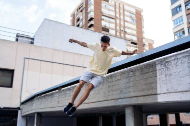 Serin ve kendinden emin çocuk şehirde parkur numaraları yapıyor ve eğleniyor..