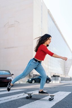 Genç kaykaycı kadın şehirde sörf tahtası ile pratik yapıyor ve eğleniyor..
