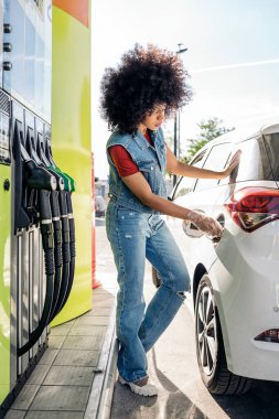 Benzin istasyonunda arabasını benzinle dolduran afro saçlı havalı siyahi kadın..