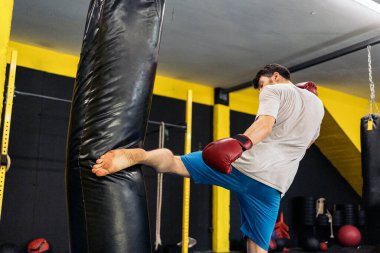 Kickboks dövüşçüsü spor salonunda ayaklarıyla kum torbasına tekme atıyor. Kickboks kavramı.