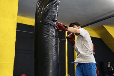 Tanımlanamayan kickboks dövüşçüsü spor salonunda kum torbasına yumruk atıyor. Kickboks kavramı.