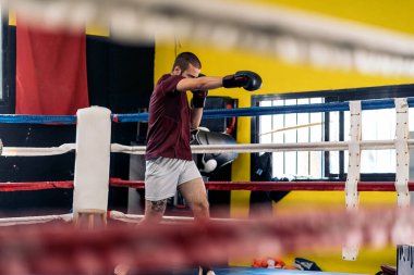 Beyaz, genç, yetişkin bir adam spor salonunda ringde egzersiz yapıyor. Kutu ve kickboks kavramı.