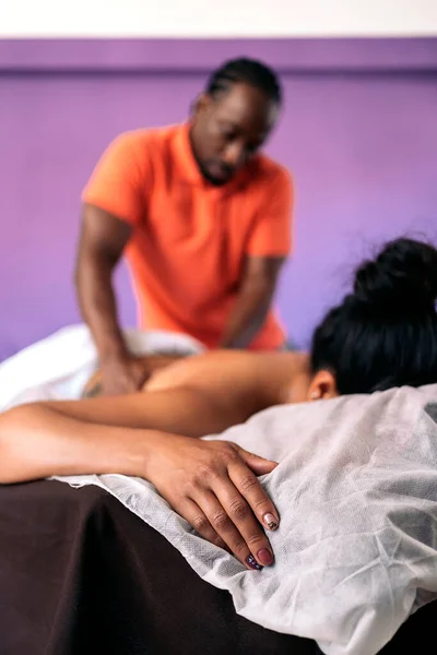 Professional spa worker giving body massage and using oil massage to an unrecognized female client.