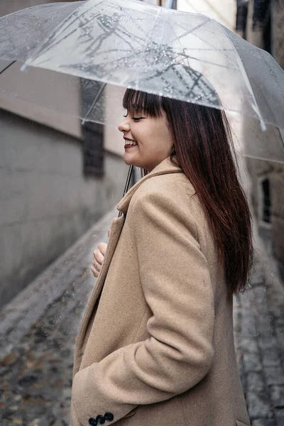 下雨天 年轻女子举着雨伞 在街上笑着 她穿着一件外套 — 图库照片