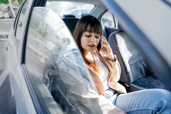 Młoda Kobieta Siedzi Samochodzie Rozmawia Przez Komórkę Sobie Makijaż Ubranie — Zdjęcie stockowe