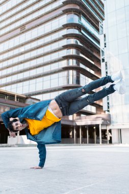 Sıradan kıyafetleri olan yetenekli genç adam, sokaktaki büyük modern binalara karşı ara veriyor..