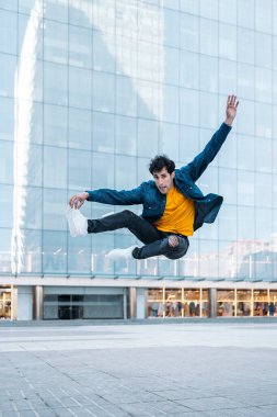 Sıradan kıyafetleri olan yetenekli genç adam, sokaktaki büyük modern binalara karşı ara veriyor..