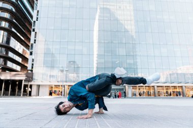 Sokakta pratik yapıp eğlenen havalı break dansçı. Dans ediyor ve kameraya bakıyor..