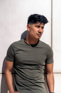 Havalı Latin adam günlük kıyafetler giyip beyaz duvara bakıyor..