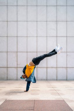 Harika bir dansçı sokakta beyaz duvara yaslanıp kameraya bakıyor..