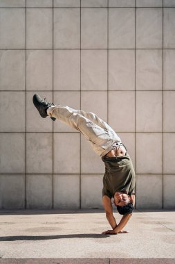 Sokakta break dans yapan havalı genç Latin adam yeteneğini gösteriyor. Kameraya bakıyor..