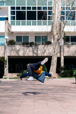 Tanınmayan genç adam parkta break dans yapıyor ve eğleniyor..