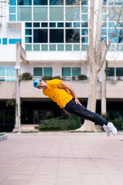 Kendine güvenen genç adam parkta break dans yapıyor ve eğleniyor..