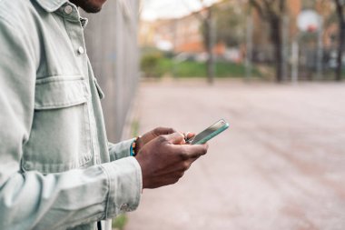 Sokakta dikilen ve cep telefonunu kullanan tanınmamış genç bir Afrikalı..
