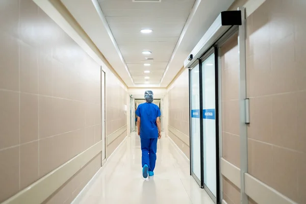 Rear view of a doctor in uniform walking along a corridor in the hospital
