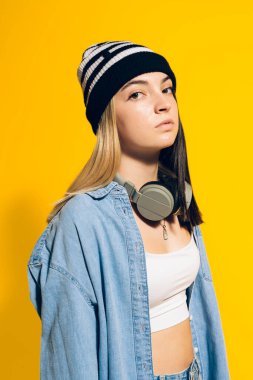Stock photo of young expressive girl looking at camera in studio. She is wearing headphones.