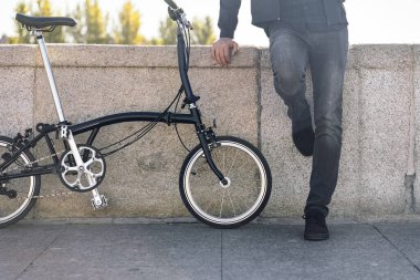 Sokakta kaldırılabilir bisikletiyle duran suratsız adamın resmi..