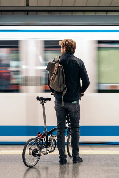 Stock photo of young man in the metro holding his detachable bike.