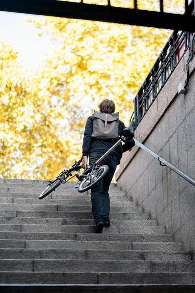 Stock photo of unrecognized man going up the stairs with his bike.