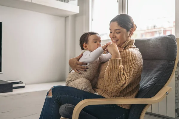 Stock photo of young mother sharing cute moment with her little baby in the living room.