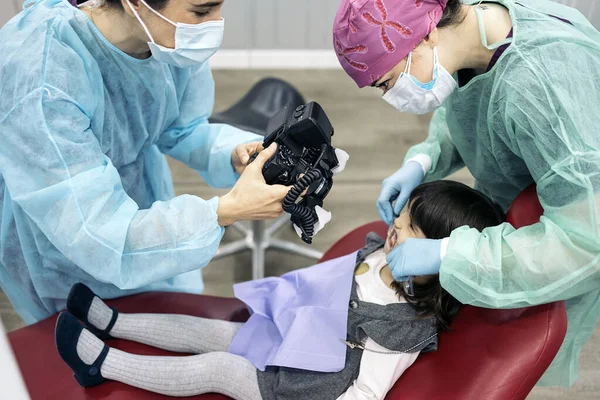 若い患者の顔のマスクを身に着けている女性歯科医のストック写真 — ストック写真