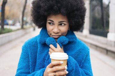 Stock photo of beautiful african american girl with a cup of coffee enjoying winter day in the city.