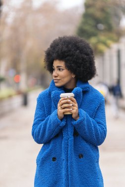 Stock photo of cool afro girl looking to the side and having a cup of coffee.
