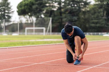 Stock photo of disabled man athlete taking a break and tying his trainers. Paralympic Sport Concept.